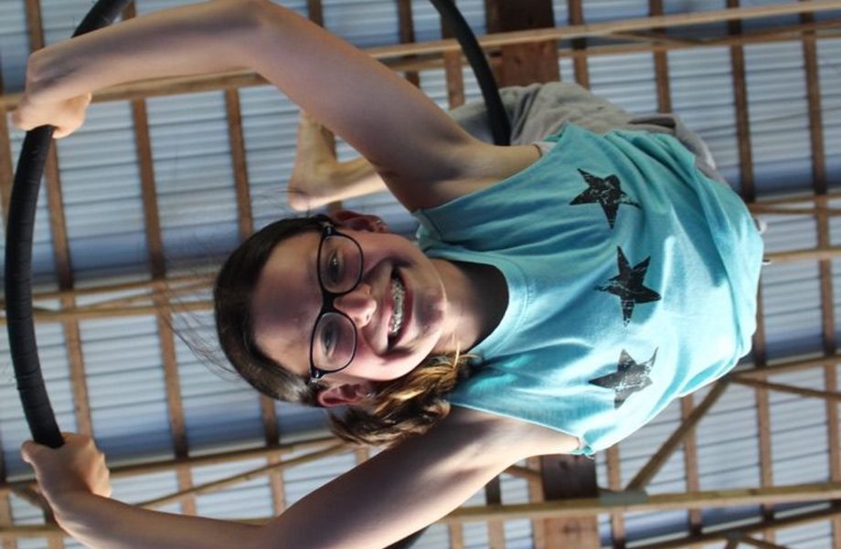 A girl on a hoop smiling.