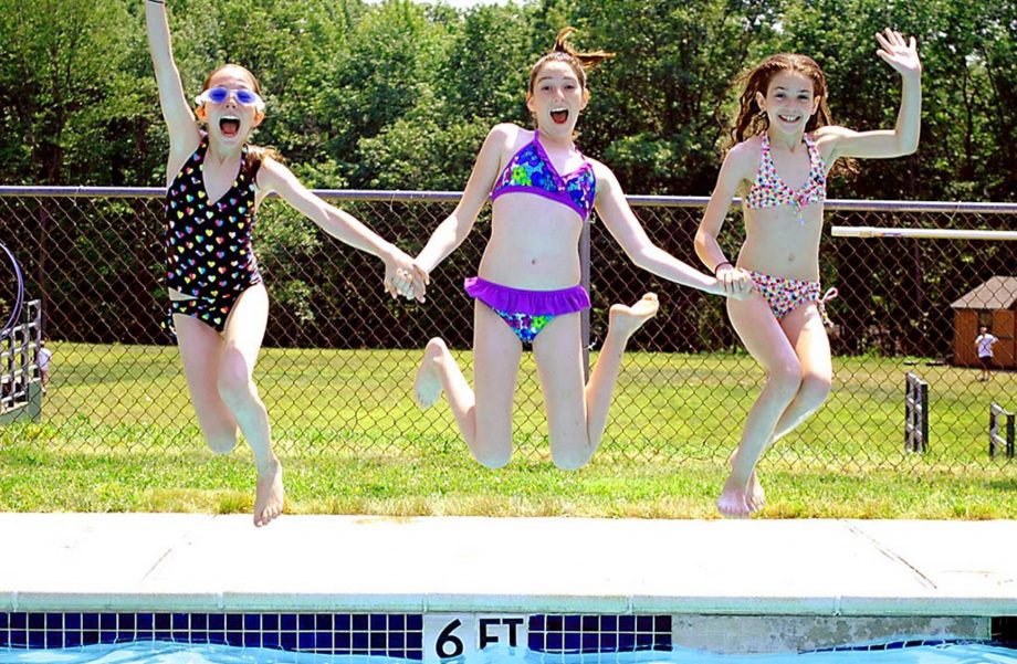 Girls holding hands and jumping into pool