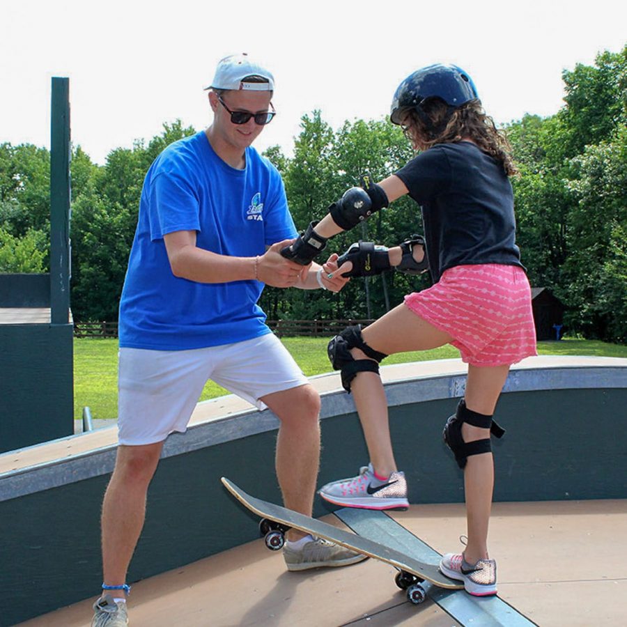 girl camper skateboarding with instructor