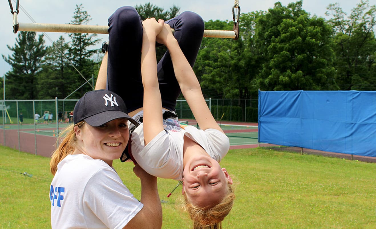 Staff helping camper on trapeze